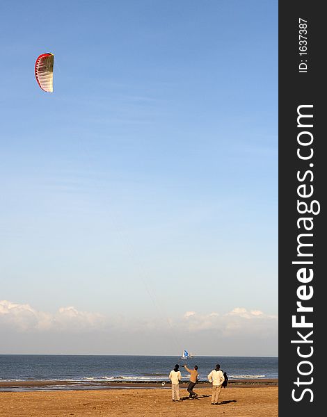 3 friends flying a kite on the beach