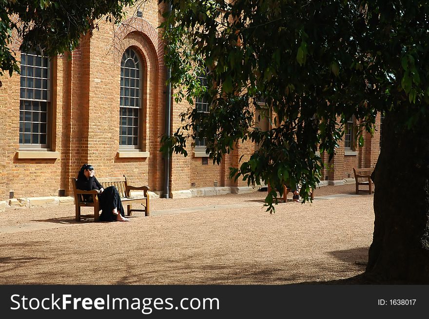 Mourning woman sitting on a wooden bench in front of a church. Mourning woman sitting on a wooden bench in front of a church