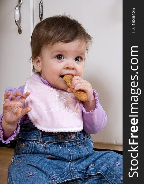 Adorable baby on the kitchen floor enjoying a cookie. Adorable baby on the kitchen floor enjoying a cookie.