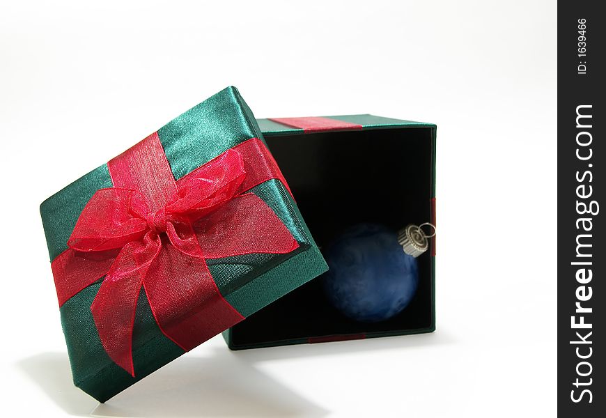 Photo of a green christmas present with a red bow and a blue ornament inside isolated on a white background. Photo of a green christmas present with a red bow and a blue ornament inside isolated on a white background