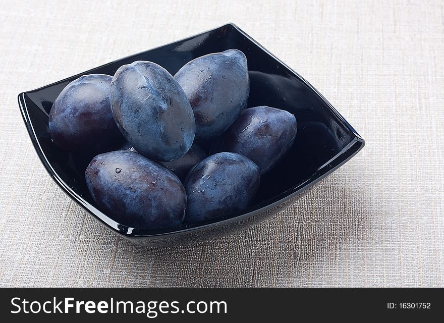 Black glass bowl with plums