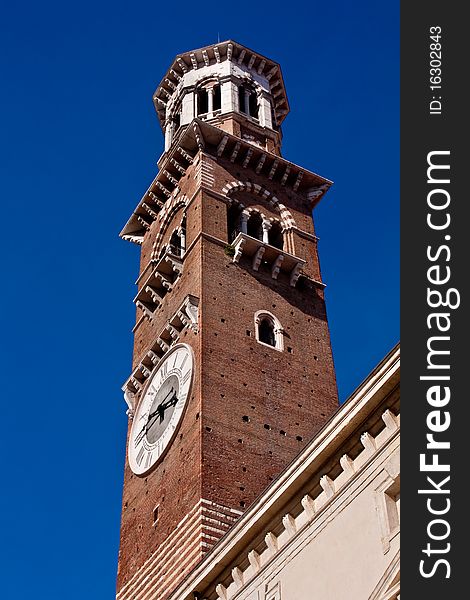 Lamberti tower in Verona isolated against a deep blue sky. Shows clock face