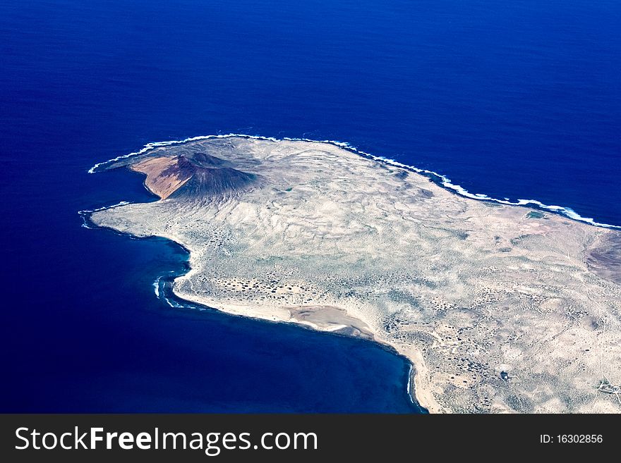 Aerial view of Lanzarote. Deep blue sea and a volcano with a desert landscape. Aerial view of Lanzarote. Deep blue sea and a volcano with a desert landscape
