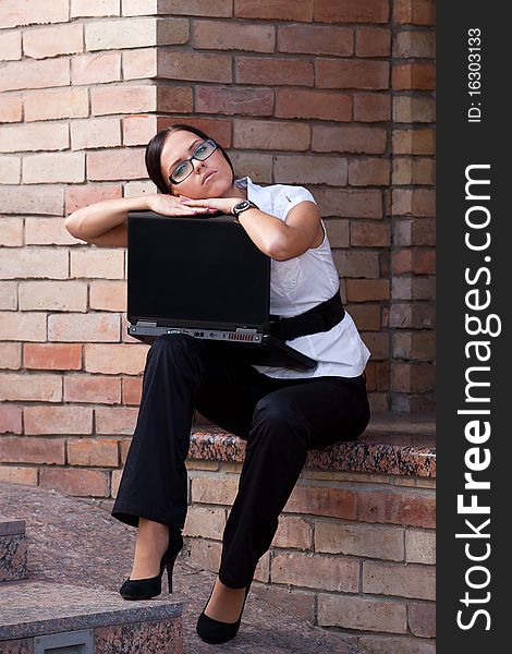 Businesswoman sitting with laptop agains brick wall of the office building. Businesswoman sitting with laptop agains brick wall of the office building