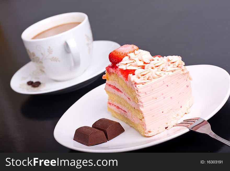 Strawberry cake dessert with cup of cafe on black background