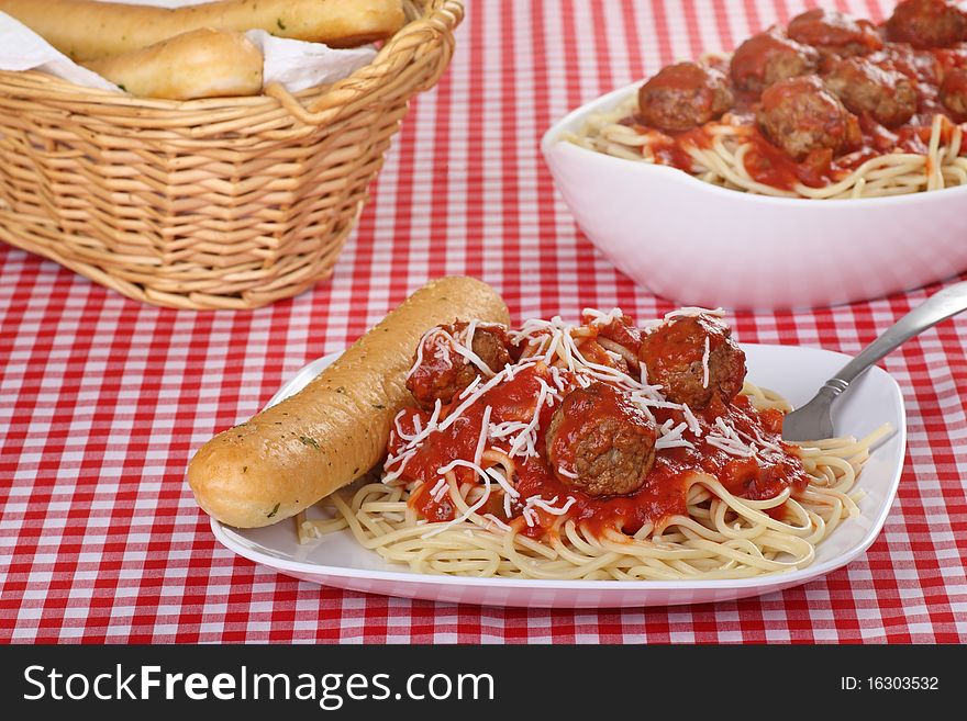 Spaghetti covered with tomato sauce, meatballs and cheese with breadsticks. Spaghetti covered with tomato sauce, meatballs and cheese with breadsticks