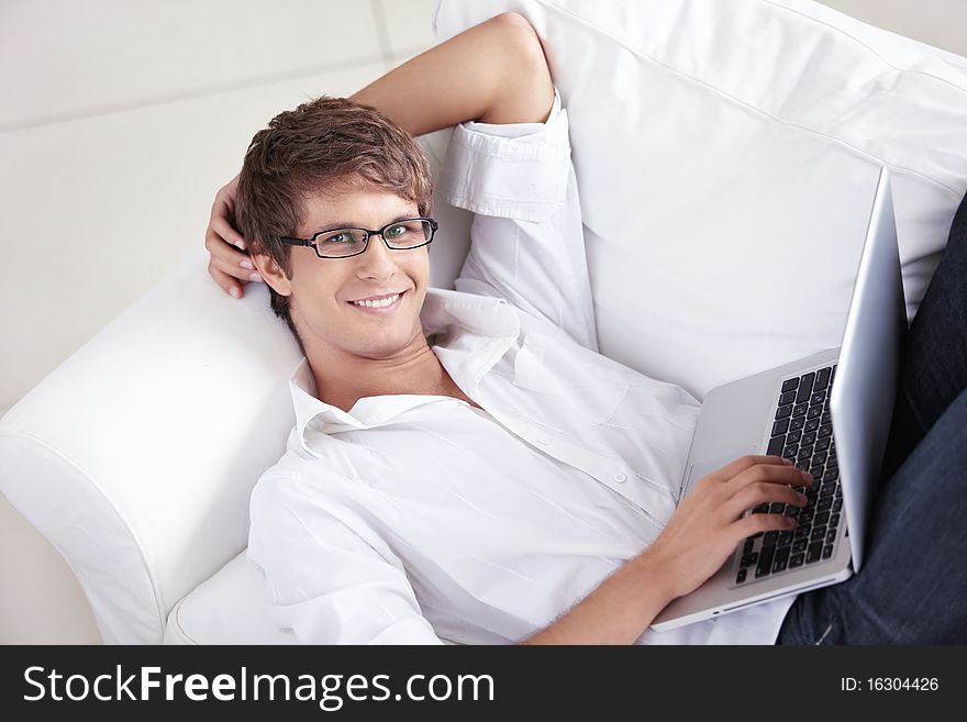 Attractive man with laptop on a couch. Attractive man with laptop on a couch