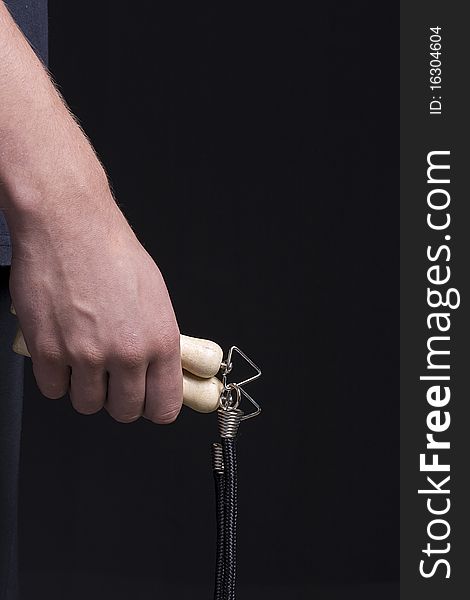 Human hand holding a jump rope on a black background.