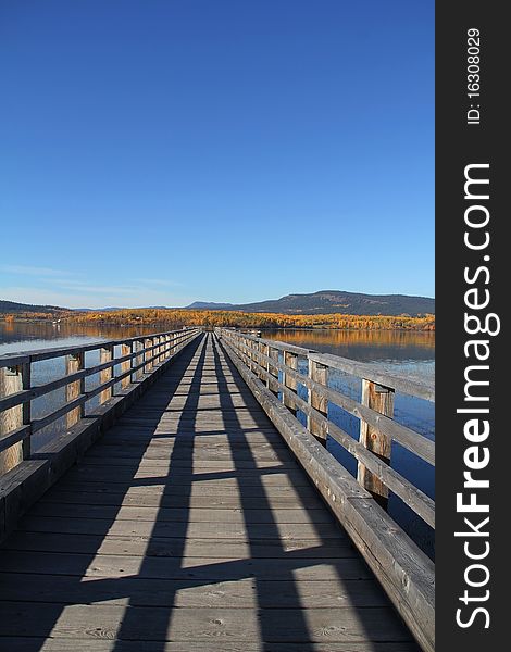 Long wooden Pier stretches into lake with autumn reflections. Long wooden Pier stretches into lake with autumn reflections