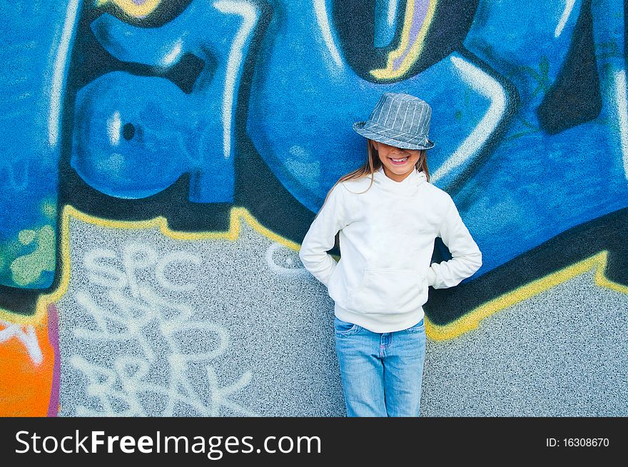 Fashionable stylish beautiful girl standing near a wall with graffiti. Outside. Fashionable stylish beautiful girl standing near a wall with graffiti. Outside