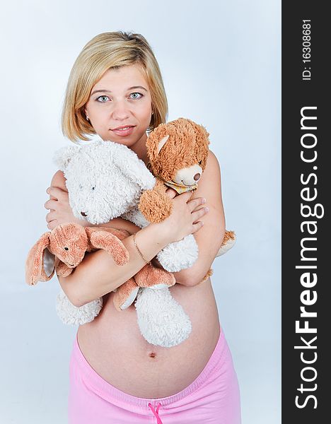 Sweet pregnant girl with toys in the studio