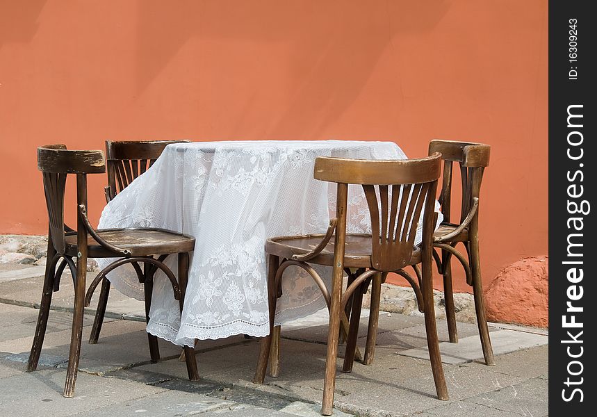 Covered with white table-cloth table and four chairs. Scene before cafe. Covered with white table-cloth table and four chairs. Scene before cafe.