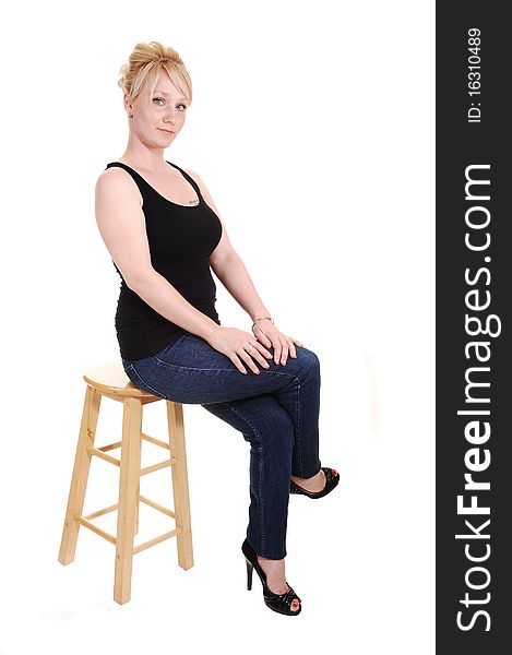 An pretty blond woman in jeans and a black tank top sitting in the studio, looking into the camera, for white background. An pretty blond woman in jeans and a black tank top sitting in the studio, looking into the camera, for white background.