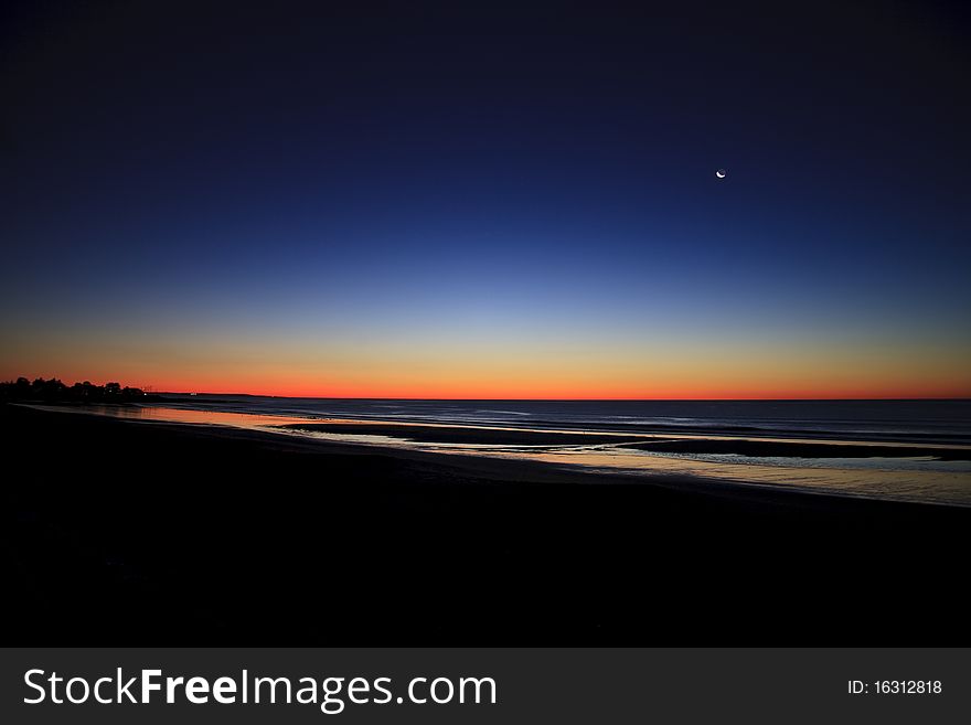 Exposed horizon and water with setting moon right before sunrise in Maine. Exposed horizon and water with setting moon right before sunrise in Maine