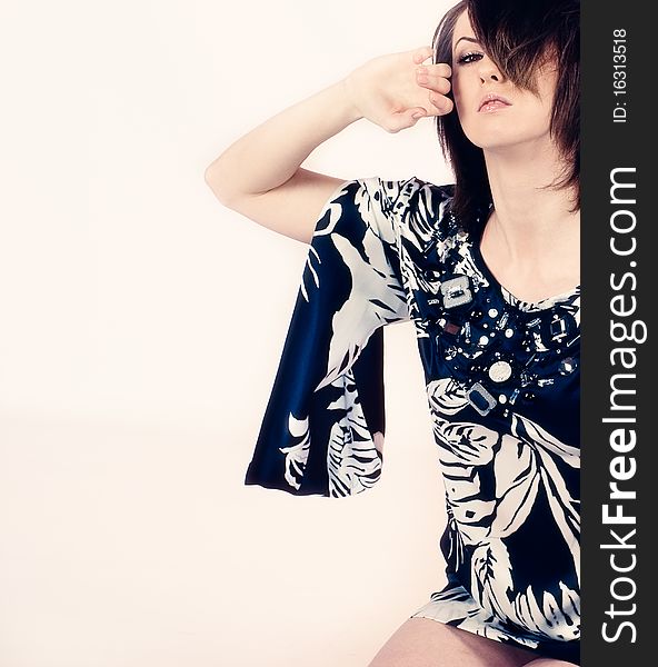 Studio shot of a young, beautiful, brunette , fashionable woman in dress sitting on the floor