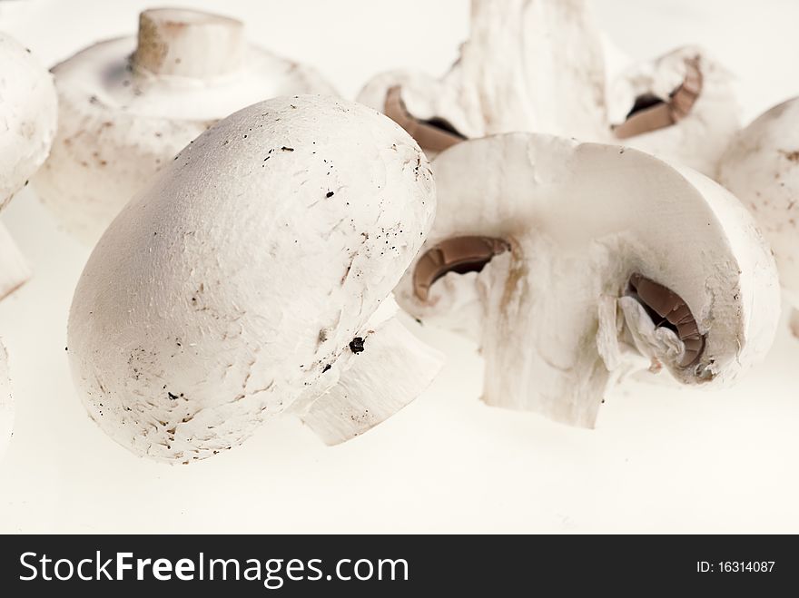 A bunch of brown champignons and a cut one on a white background