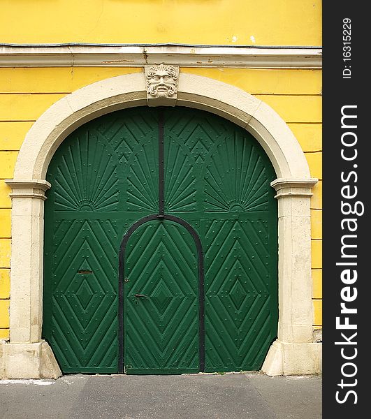 Old wooden door painted green, with carved stone frame and yellow wall. Old wooden door painted green, with carved stone frame and yellow wall
