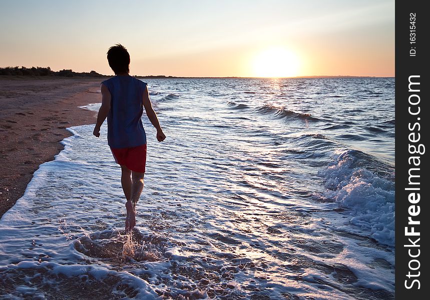 Teen boy runs at the beach on beautiful summer sunset. Teen boy runs at the beach on beautiful summer sunset