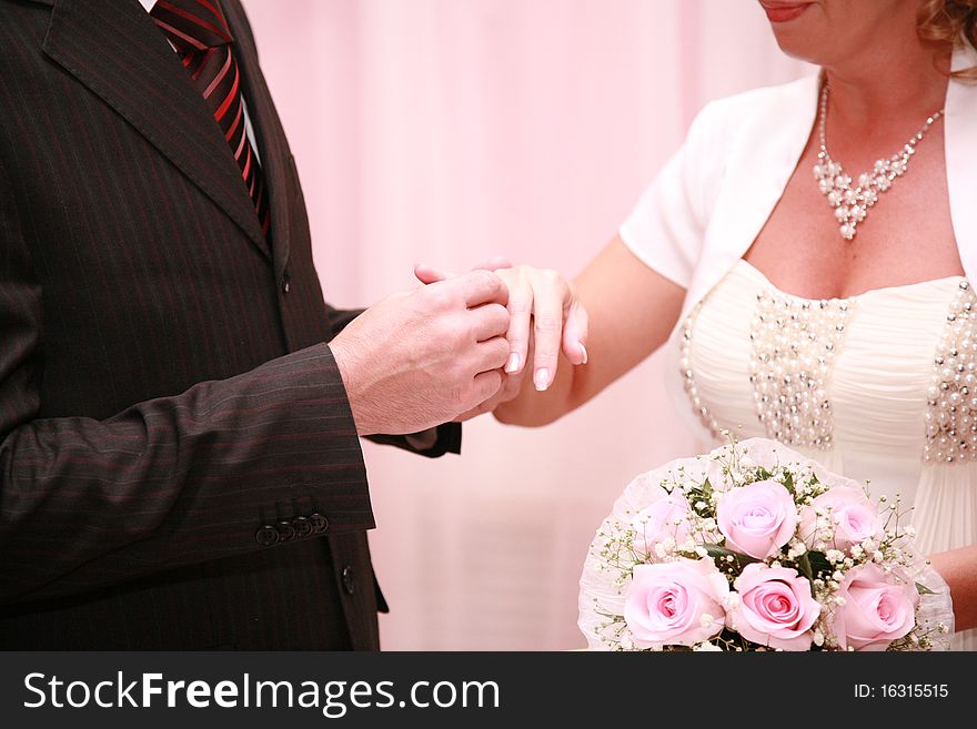 The groom puts on a ring to the bride in a registry office