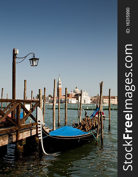 A Venetian boat by a jetty or landing stage on a sunny day. A Venetian boat by a jetty or landing stage on a sunny day.