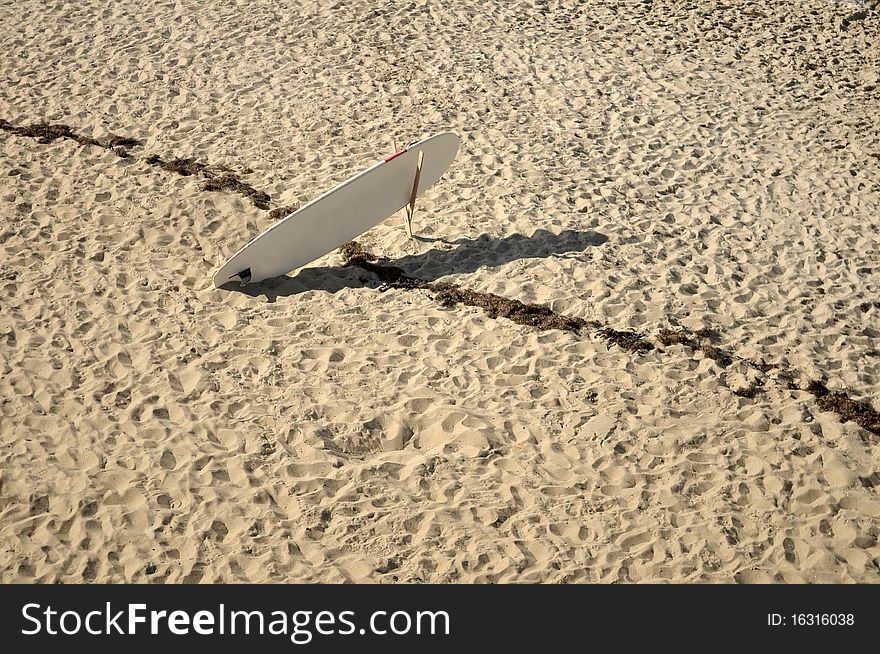 One surfboard only in the sand viewed from above. One surfboard only in the sand viewed from above.