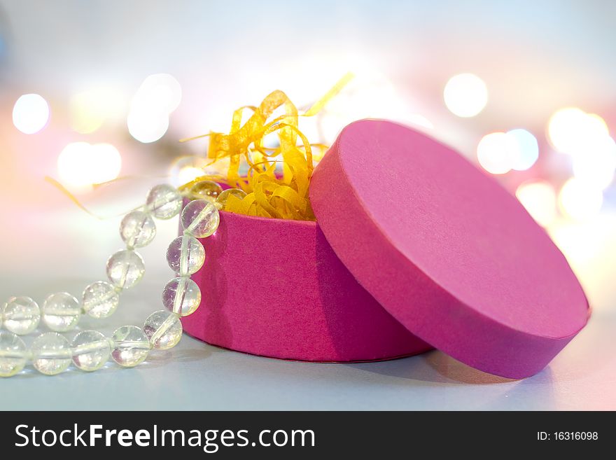 Pink oval gift box and crystal beads with light dots background. Pink oval gift box and crystal beads with light dots background