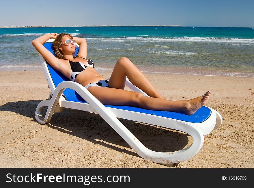 Cute woman on a plank bed at the sea