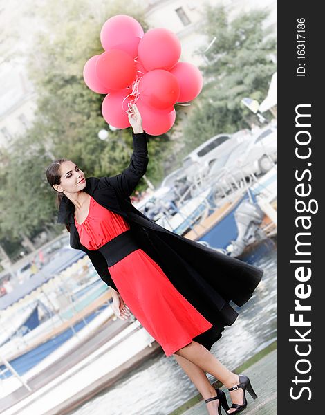 Young happy woman with red balloons on pier background