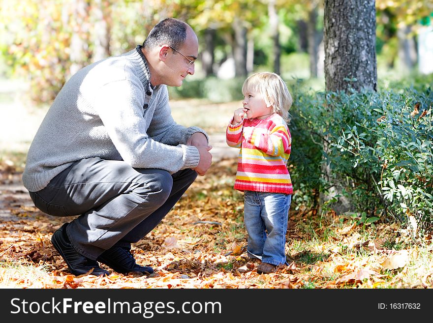 Father and daughter looking at each other on autumn park background. Father and daughter looking at each other on autumn park background