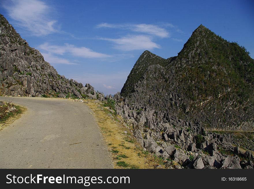 A road in the karst desert in northern Vietnam . The road climbs into the mountains among the rocks that look like a bubbling water which would freeze suddenly. A road in the karst desert in northern Vietnam . The road climbs into the mountains among the rocks that look like a bubbling water which would freeze suddenly