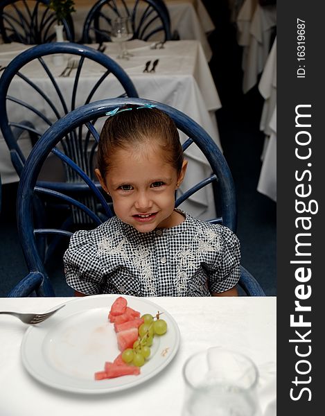 A sweet child sitting at table in a restaurant smiling. A sweet child sitting at table in a restaurant smiling