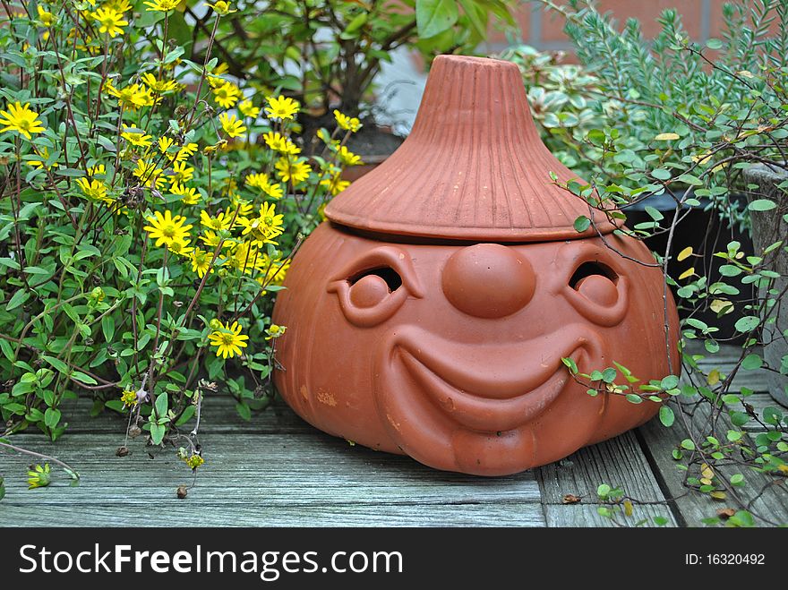 Still life with a terracotta oignon head on a wooden table between some plants. Still life with a terracotta oignon head on a wooden table between some plants