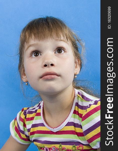 Serious girl looks upwards on a blue background