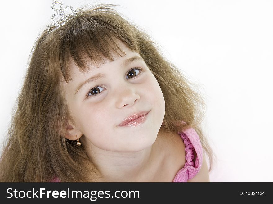 The girl the princess in a pink dress sits opposite to a white background. The girl the princess in a pink dress sits opposite to a white background