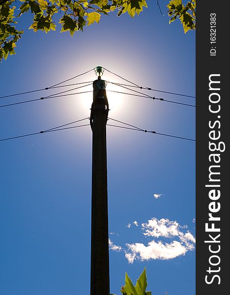 Electrical pylon over a blue sky and sun for green energy