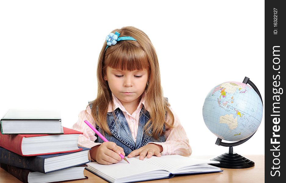 The girl sits at a table and writes to writing-books