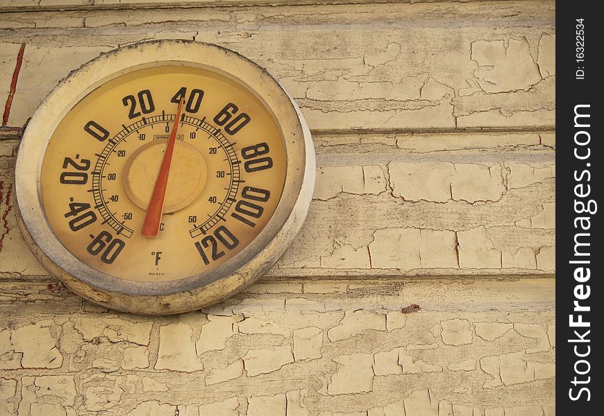 Yellow temperature gauge on a yellow wall. The gauge is old but working. The wall paint is cracked and peeling off. Yellow temperature gauge on a yellow wall. The gauge is old but working. The wall paint is cracked and peeling off.