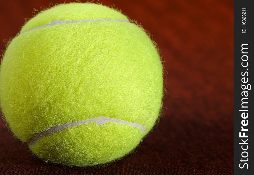 Tennis ball on the orange surface, closeup shot, for various, tennis,recreation and sport themes