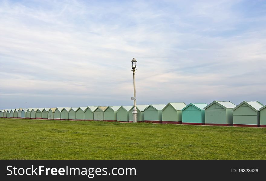 A view of along row of beach huts with grass and sky