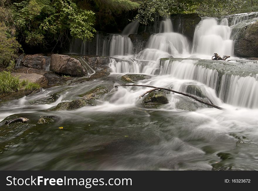 Long exposure of a waterfall with a wooden stick from a branch. Long exposure of a waterfall with a wooden stick from a branch.