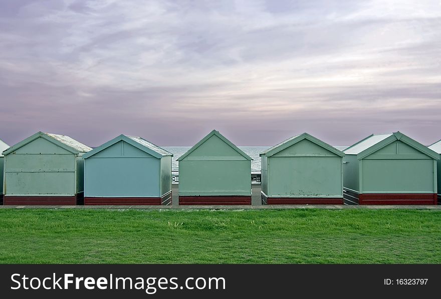 A voew of the back of beach huts with grass and sky