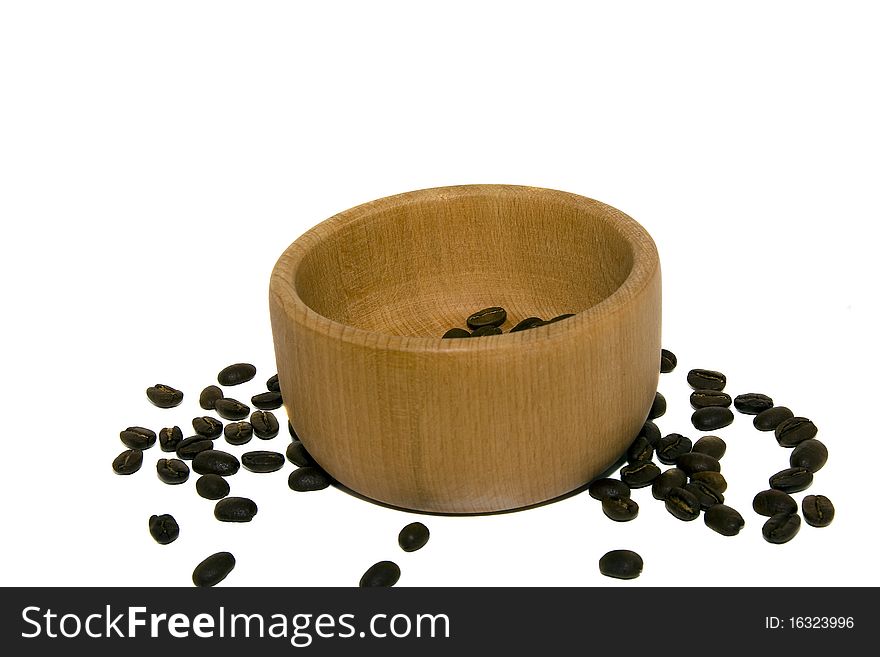 The grains of coffee scattered near a wooden bowl. The grains of coffee scattered near a wooden bowl