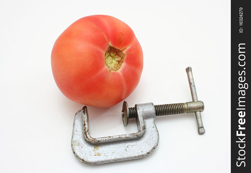 The red tomato and metal clamp lie nearby on a white background. The red tomato and metal clamp lie nearby on a white background