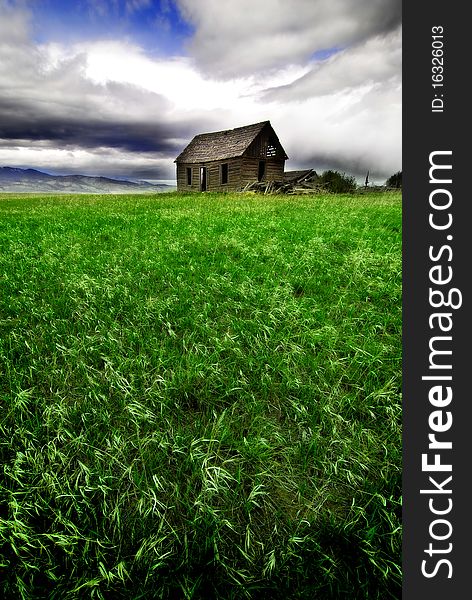 Old cabin in field with storm clouds in sky. Old cabin in field with storm clouds in sky