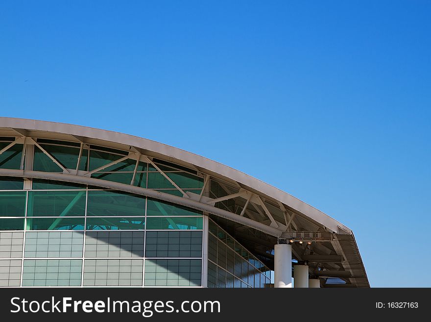 Arched roof sports complex building aginst a cloudless blue sky. Arched roof sports complex building aginst a cloudless blue sky
