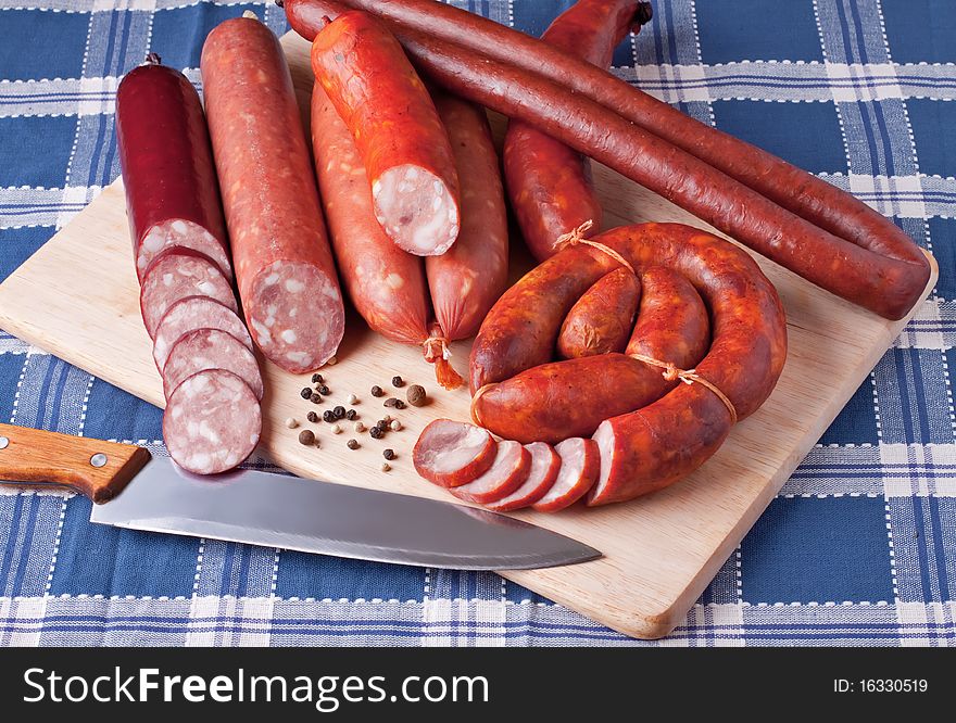 A variety of processed cold meat products, on a wooden cutting board. A variety of processed cold meat products, on a wooden cutting board.