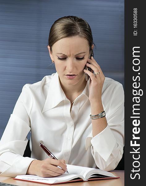 Concentrated businesswoman listening bad news on the phone sitting at her desk in office