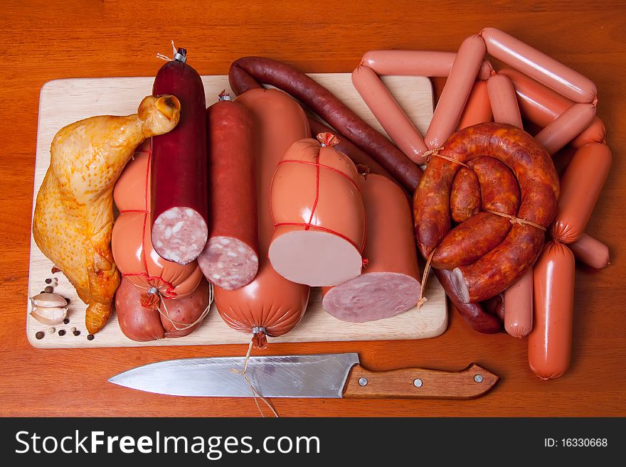 A variety of processed cold meat products, on a wooden cutting board. A variety of processed cold meat products, on a wooden cutting board.