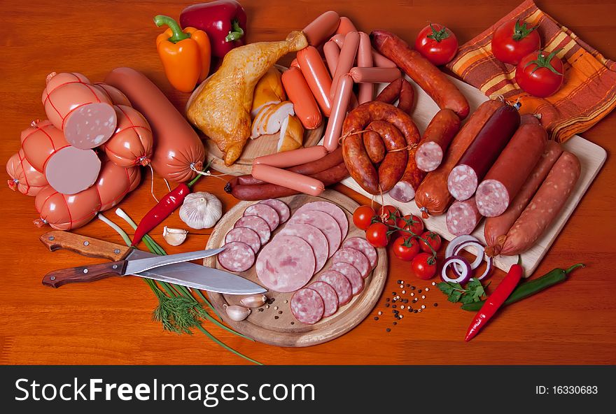 A variety of processed cold meat products, on a wooden cutting board. A variety of processed cold meat products, on a wooden cutting board.