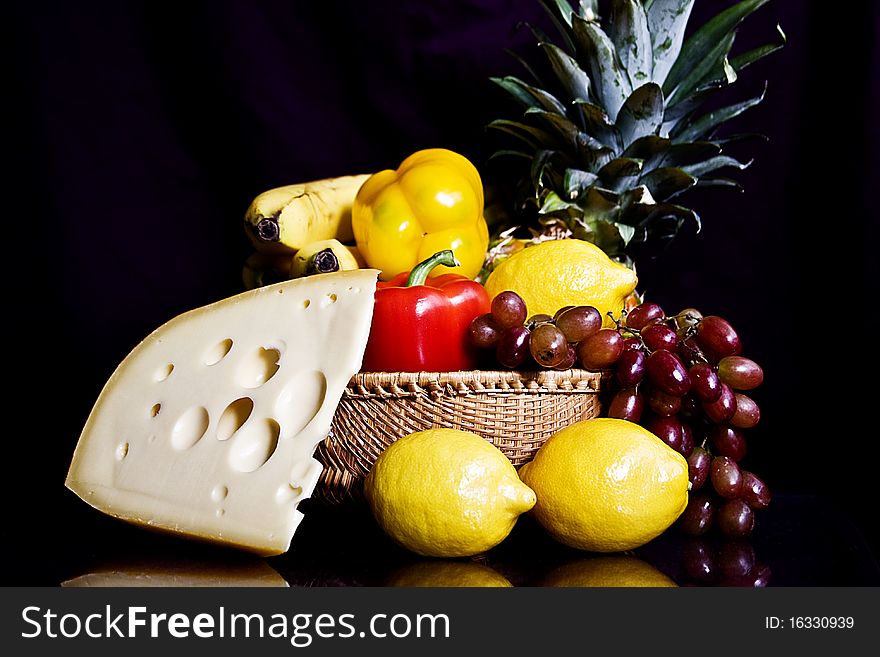 Fruit in basket still life cheese with holes lemons yellow bell peppers shiny purple grapes whole pineapple in woven basket. Fruit in basket still life cheese with holes lemons yellow bell peppers shiny purple grapes whole pineapple in woven basket